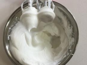蛋白里面加入2滴白醋和白糖30克，用电动打蛋器先高速打发蛋白，感到蛋白有厚重感了改为中速打发蛋白，直到打到像图片上这样蛋白打发到有坚挺的小尖角了，再改为低速打发几下，整理一下蛋白里面的气泡。（打发蛋白的时候可以把烤箱预热着！）