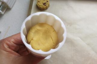 然后把月饼模具提前刷上一层融化的黄油或植物油，再取一份豆沙团放入模具中用手稍微压一下。