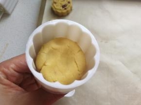 然后把月饼模具提前刷上一层融化的黄油或植物油，再取一份豆沙团放入模具中用手稍微压一下。