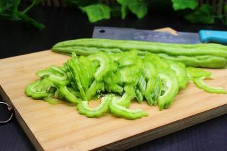 挑选好新鲜的苦瓜，颗粒越大且饱满，纹路清晰，这样的苦瓜不会太苦。洗净，从中间切开，去苦瓜瓢和苦瓜籽，然后斜切，斜切可以让苦瓜哦，这是切菜技巧。