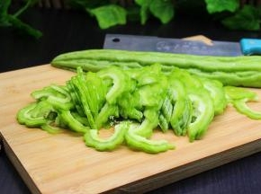 挑选好新鲜的苦瓜，颗粒越大且饱满，纹路清晰，这样的苦瓜不会太苦。洗净，从中间切开，去苦瓜瓢和苦瓜籽，然后斜切，斜切可以让苦瓜哦，这是切菜技巧。