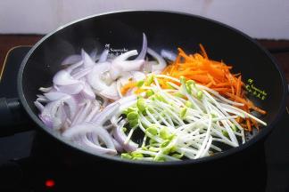 用平底锅热锅，倒一点油，放入切好的洋葱、胡萝卜，还有洗净的豆芽，一起煸炒出香味。炒至洋葱、胡萝卜、豆芽都变软的时候即可。