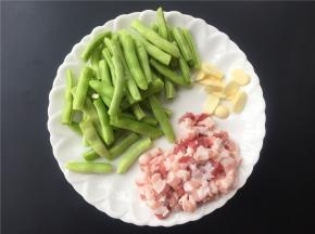 将大蒜切片，五花肉切小颗粒，四季豆去筋拆小段。