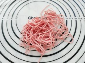 将粉色面片压成最细的面条。