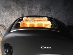 将吐司片插入到多士炉的吐司槽中，选择所需的烧色