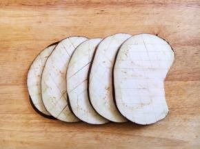 茄子洗干净，去蒂，把茄子切成1厘米的厚片，在每片茄子的正反两面轻轻划上棋子格，划2mm深。