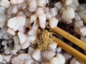 鱿鱼块儿加入适量的料酒、盐、十三香搅拌均匀腌制十五分钟