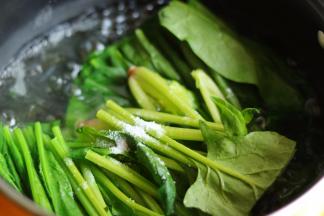 汤锅加水烧开后，加少许盐和几滴油，下入菠菜段煮30秒，至菠菜变软即可。加入油和盐可以让菠菜保持碧绿的颜色。