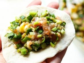取一个饺子皮，放上适量肉馅。