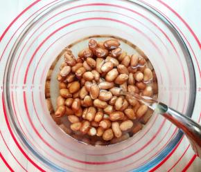 花生米装在料理碗中，倒入能淹没过花生米的开水，开水没有规定多少，能淹没过就可以了，为什么要用开水而不是冷水泡呢？用开水烫出来的皮它会迅速变皱和花生米形成脱离的状态，然而就容易脱落。而用冷水泡的花生米只会慢慢的使花生米饱满，这样反而更难使花生皮和花生米脱离，所以我是采用了开水烫的哦