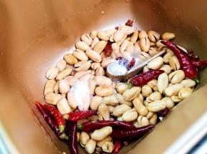 面包机启动炒干果功能，面包机桶内倒入20g的花生油，把花椒，干辣椒冷油放入，加热至搅拌叶搅动就可倒入烤好的花生米，然后就开始调味了，加入盐啦，再加入细砂糖啦
