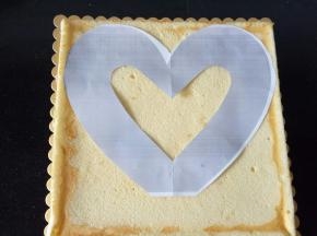 晾凉后的蛋糕胚放底托上，a4纸打印一个心形，剪下来，拿一个小刀沿着心形将蛋糕进行分割