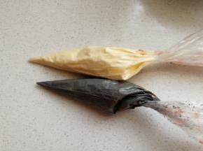 然后把拌好的竹炭蛋糊装入裱花袋中，再取同样分量的原色蛋糊也装入裱花袋备用。