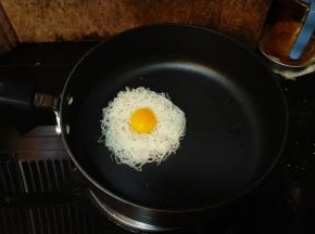 米粉用热水泡软打散后放入蒜盐拌均匀；不粘锅放入少许油，将米粉放入整成圆形，打入整只鸡蛋