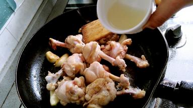 锅里放油，放入姜片，蒜子，油烧热炸出香味，放入鸡翅根煎至表面微黄，没有血色，加入米酒或料酒