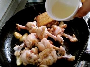 锅里放油，放入姜片，蒜子，油烧热炸出香味，放入鸡翅根煎至表面微黄，没有血色，加入米酒或料酒