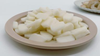 年糕切成厚薄一致的片。