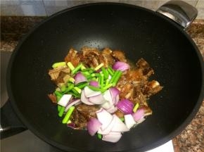 接着放入蒜苔和洋葱翻炒1分钟。