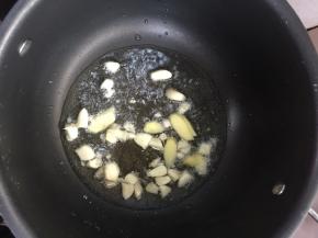 汤锅烧热倒入适量的油，放入蒜瓣和姜片炝锅。