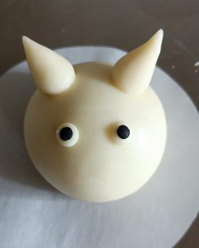 搓两粒芝麻大小的黑色面团，抹少许牛奶粘在上面轻轻压扁