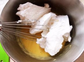 取一部分打发好的蛋白加入到蛋黄糊中，先用蛋抽翻拌均匀