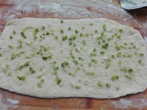 将擀好的面片上面，均匀的抹上前面我们做好的油酥，如图所示。喜欢吃葱香味道的，还可以提前将葱花放点芝麻，放适量盐混合一下，然后同样均匀的洒在擀好的面片上面。