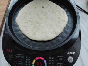 煎烤机提前预热，选择馅饼功能，底盘刷层底油，将其擀好的饼胚放入。