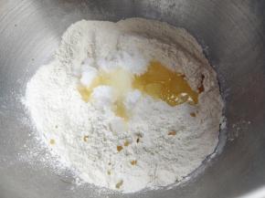 用金龙鱼高筋粉覆盖住酵母粉后，加入糖、盐、植物油和鸡蛋，蛋液需留出一勺，后面会用到。不要让盐糖直接接触酵母，会影响酵母的发酵效果。