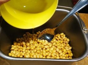 调好的菌粉倒入晾至40度左右的黄豆中，用汤匙翻拌均匀