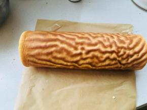 虎皮纹路反面涂上打发的淡奶油，取出之前冷藏的蛋糕卷，将虎皮部分卷在蛋糕卷上。包裹油纸，放入冰箱冷藏定型。定型时间一小时以上。