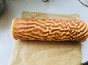 虎皮纹路反面涂上打发的淡奶油，取出之前冷藏的蛋糕卷，将虎皮部分卷在蛋糕卷上。包裹油纸，放入冰箱冷藏定型。定型时间一小时以上。