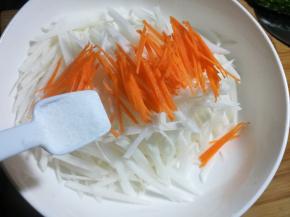 5 把胡萝卜和白萝卜放大的碗里，加入一勺盐，用手抓均匀，腌渍十分钟，挤去多余的水分。