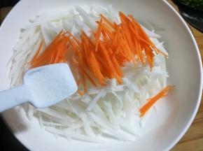 5 把胡萝卜和白萝卜放大的碗里，加入一勺盐，用手抓均匀，腌渍十分钟，挤去多余的水分。