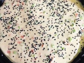 在面糊表面均匀的撒上适量的黑芝麻。