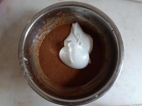 舀一勺蛋白霜与可可面糊翻拌。