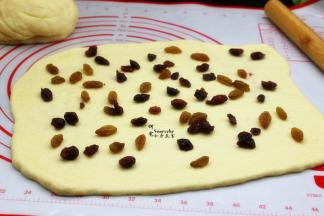 把洗干净的葡萄干、切碎的蔓越莓干均匀铺在面片上。