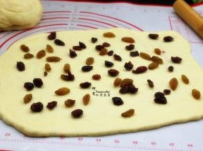 把洗干净的葡萄干、切碎的蔓越莓干均匀铺在面片上。