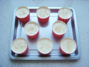 把蛋糊倒入裱花袋中，挤入纸杯里至八九分满，表面撒上少许熟芝麻。