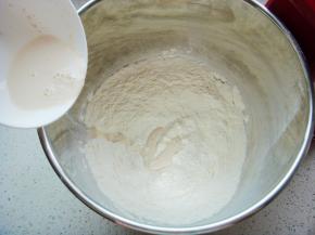 面粉倒入搅拌桶里加入盐，酵母粉用分量内的牛奶搅拌融化倒入面粉中。