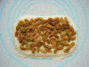 取一份擀成长方形的面片，边缘处压薄利于封口。铺上提前泡软的葡萄干。