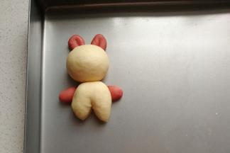 再把头部和身体部分移入烤盘拼装起来，接着把小兔子的耳朵和手也拼装起来。（注意耳朵是压在头部下，手是压在身体下拼装的）