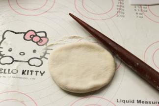 揉面垫上面撒干粉，取一个面剂子，先按扁，像擀饺子皮一样擀成略大点的厚片。