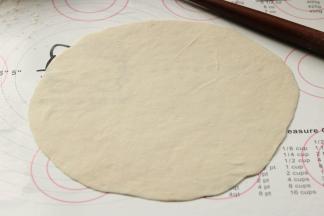 开始转圈把饼推的大一点。右手拿着小擀面杖的一端，左手辅助把饼卷到擀面杖上，然后左手向前推，再返回，返回的同时把饼打开，略微转换一下角度继续刚才的过程，这样转够一圈，饼就会变的大而均匀。记得擀的时候一定要撒干粉操作，避免粘在一起，如果干粉变少了，及时补充。把4个面剂子都擀成饼待用。