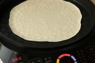 打开盖子，放入一个饼胚，大约1分钟后，会看到饼上面鼓起小小的白泡，这时候开始翻第一次面。