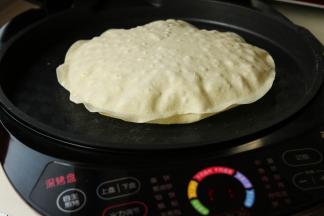 又过去2分钟，整个饼都鼓起来了。而且表面伴随着焦斑。这时候可以随意的两面翻翻，等到两面的焦斑大致一样之后就可以拿出来了。重复这个过程，把四个饼都做好，并且摞在一起放置。