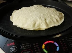 又过去2分钟，整个饼都鼓起来了。而且表面伴随着焦斑。这时候可以随意的两面翻翻，等到两面的焦斑大致一样之后就可以拿出来了。重复这个过程，把四个饼都做好，并且摞在一起放置。