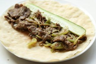 刚才烙好的饼，放上煎好的黑椒牛肉片，再放一根黄瓜条。