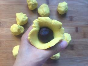 豆沙分成12克一个，将面团压扁，把豆沙包入