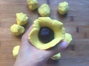 豆沙分成12克一个，将面团压扁，把豆沙包入