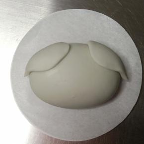 抹少许牛奶粘贴在面团上方两侧，轻轻用手指压平